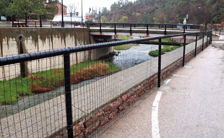A permanent 400-foot barrier has now been installed along the river channel retaining wall in front of Springs Lodge. Photo by Brett Nachtigall/Fall River County Herald-Star