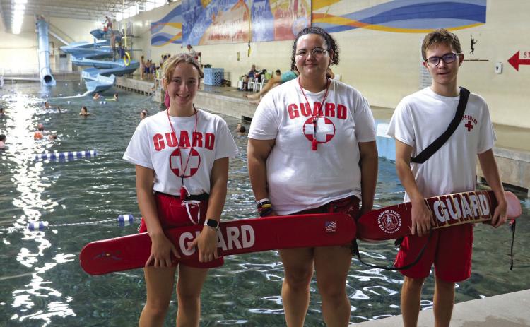 Evans Plunge Mineral Springs lifeguards Zoe Givler, 17 (left), and Ian Clyde, 16 (right), surround Aquatics Director Okoye Zimiga (center) inside the pool area near the rings where the three of them, among others, were involved in a successful rescue when a patron passed out and fell into the water. Photo by Brett Nachtigall/Fall River County Herald-Star