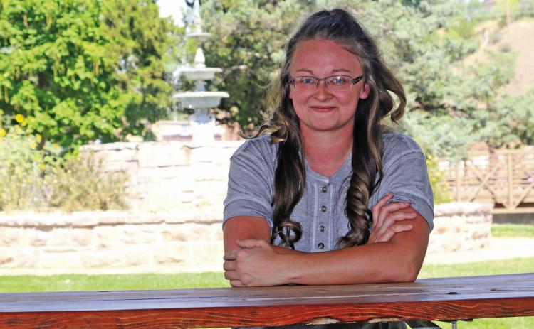 Sitting at a picnic shelter in Centennial Park, Sayer Lockhart, age 25, is currently planning a fundraiser at the park on Sept. 6 which will also serve as an opportunity for the community to come together for an evening of food, live music and fun competitions including a cornhole tournament, pie contest, pet contest and car show. Photo by Brett Nachtigall/Fall River County Herald-Star