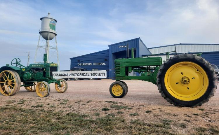 A 1929 John Deere GP and a 1941 John Deere B hold the Oelrichs Historical Society’s sign advertising their conference on April 13. Photo by Roy Merdanian