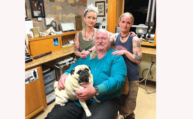 Dr. Pete Sotherland reverses roles and sits in his own dentist chair as his two daughters Becki and Jenni surround him while he holds Jenni’s pug Louie. After nearly 45 years of being a dentist in Fall River County, “Pete” is planning to retire at the end of June. Photo by Brett Nachtigall/Fall River County Herald-Star