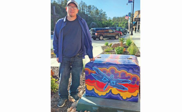 Dustin Twiss stands beside his artwork “Dragonfly Sunset” on N. River Street. A vinyl wrap was applied to the utility box as part of collaboration with Keeping Hot Springs Beautiful. Photo by Katie Merdanian/FRCHerald-Star