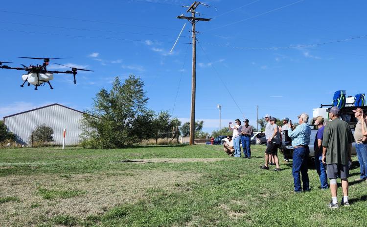 Participants at the 2025 Soil Health Workshop in Oelrichs watch as a large drone, carrying a spray tank, lifts off during a demonstration by AerSol, a Black Hills company specializing in the sale, service, and repair of drones.