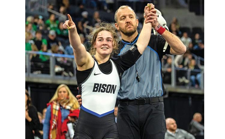 Hot Springs junior Sarah Rickenbach points to family and friends in the stands of the Denny Sanford Premier Center in Sioux Falls while getting her armed raised in victory after winning the 145 pound state wrestling championship on Saturday, Feb. 28. (Photo courtesy South Dakota Public Broadcasting)