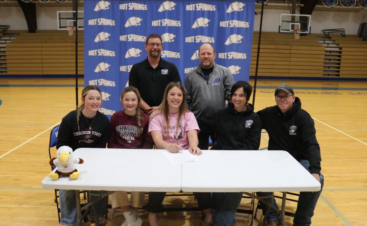 Hot Springs senior Katie Snyder, center, poses as she gets set to sign her letter of intent to wrestle at Chadron State College. Also pictured, in back, are coaches Lloyd Morgan and Ray Ringstmeyer. Seated on left, are sisters Jozee and Marley Snyder, and on right, is mom Desirae Gregerson and future step-father Sam Hanson. Photo by Brett Nachtigall/Fall River County Herald-Star