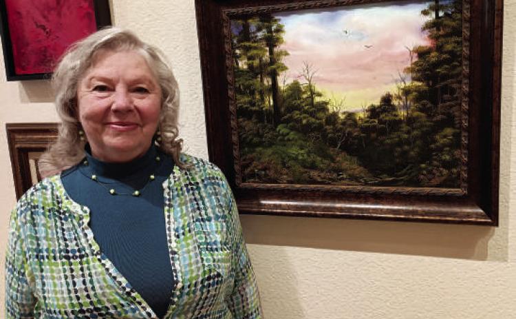 Local artist Gayle Tescher stands in front of her oil painting “Black Hills Sunset” at Art House Black Hills in downtown Hot Springs. The gallery’s “Women Artists of the Black Hills” exhibition began May 17 and runs through July 20. Photo by Marcus Heerdt/Fall River County Herald-Star
