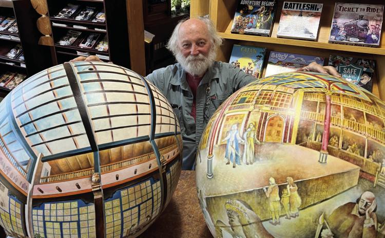 Dick Termes poses with two of his Termespheres, Santa Fe La Fonda Hotel and London’s Shakepeare’s Globe Theater, at the Hot Springs Public Library. Photo by Charity Maness/Fall River County Herald Star