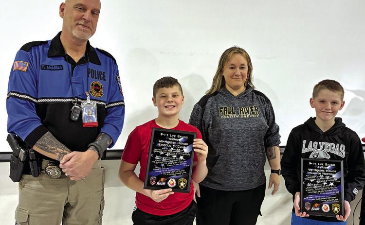 Thomas McMillan (Hot Springs Police Department School Resource Officer) and Melissa Fleming (Sheriff Dept Dispatcher) presented Lincoln McClure and Carter Norton with plaques recognizing their quick response and heroic actions for their lifesaving response. Photo by Charity Maness /Fall River County Herald Star