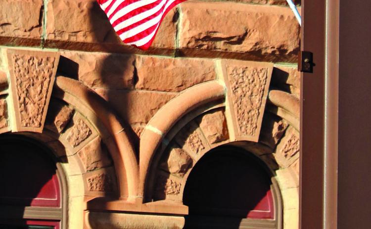 An American Flag waves from the North River Street suspended sidewalk in Hot Springs as the sandstone architecture of City Hall provides a beautiful backdrop for this scene in The Veterans Town. Photo by Brett Nachtigall/Fall River County Herald-Star