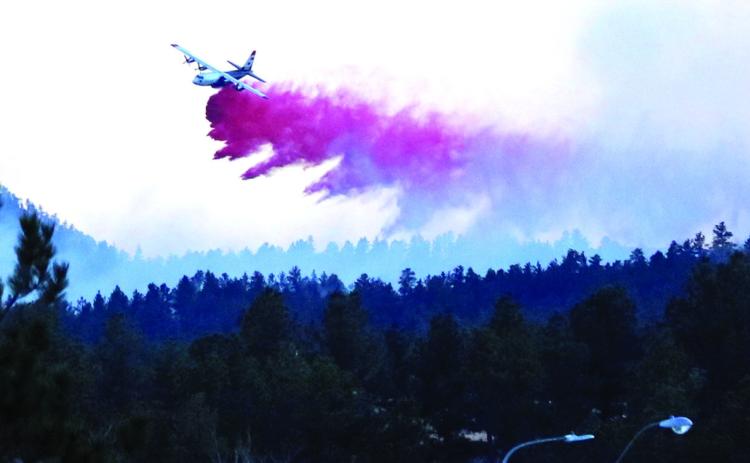 In this photo taken from Hot Springs on the corner of Lincoln Avenue and 25th Street, a U.S. Forest Service airtanker drops a load of fire retardant slurry onto the Green Acres Fire, located three miles southwest of town. The fire started on Saturday, March 1, shortly after 12 noon and was mostly contained by Monday, March 3. Photo by Brett Nachtigall/Fall River County Herald-Star