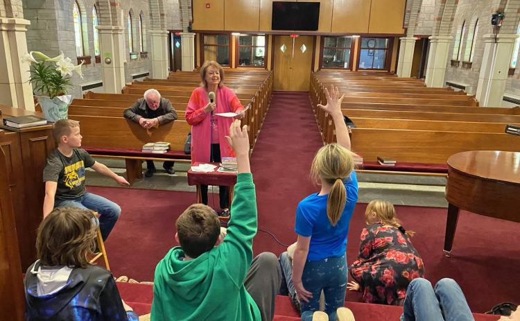 Cathy Nelson talks about journalism with the youth attending the afterschool Hang-out Program at The United Churches on Wednesday, April 3. The kids enthusiastically answer questions about who, what, where, why and how. Courtesy photo