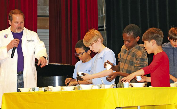 Chemist Dr. Ryan Hayes helps guide a group of young audience members as they create homemade slime while on stage during a Creation Science Symposium held at the Mueller Civic Center and hosted by the Hot Springs Seventh-Day Adventist Church. Photo by Brett Nachtigall/Fall River County Herald-Star
