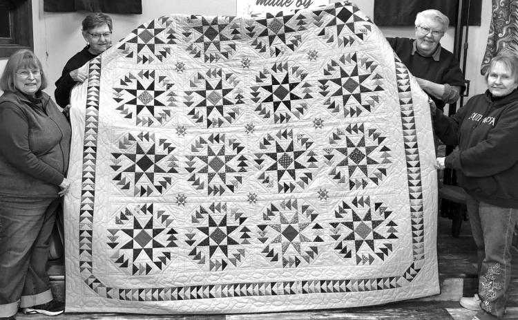 Quilters Karen Meston, Delores Hickman, Sandy Taylor and Marilyn Eighmy hold up the Minnekahta Quilters Guild 2024 raffle quilt ‘Dizzy Geese’ at their weekly hand quilters meeting. Photo by Charity Maness/Fall River County Herald Star