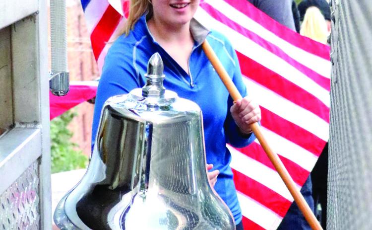 While holding the American flag, Bridget Lane of Hot Springs rings the bell mounted on a Hot Springs VA fire truck to signify reaching the top of the grand stair case during last week’s 9/11 Grand Stair Challenge. Photo by Brett Nachtigall/Fall River County Herald-Star