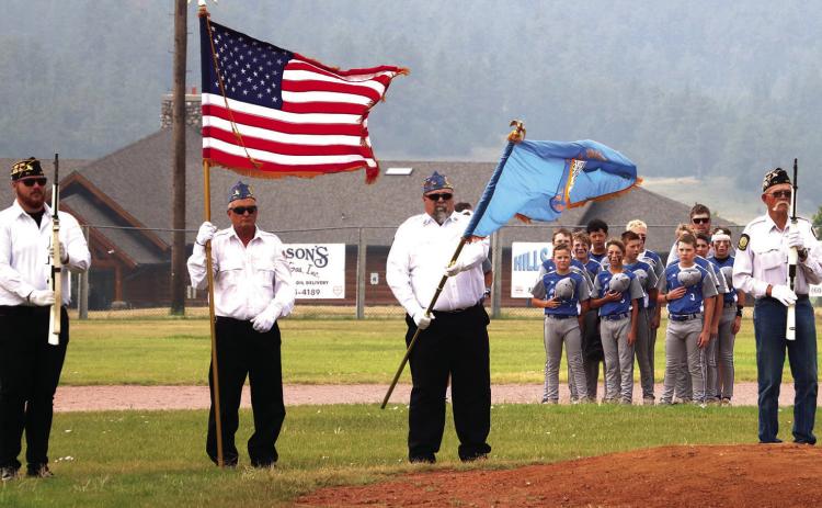 ABOVE: Members of the Hot Springs Rattlers 12u baseball team stand at attention as the National Anthem is played while the American Legion honor guard presents the colors during opening ceremonies last Friday morning. RIGHT: After the game ball was delivered by Black HIlls Life Flight, Hot Springs Mayor Bob Nelson throws out the first pitch of the tournament. Photos by Brett Nachtigall/Fall River County Herald-Star