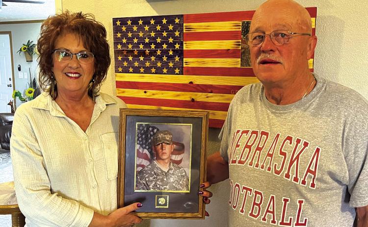 Inside their Angostura home, Julie and Jerry Roe hold a photo of their then-19-year-old son Jared who died in a drowning accident in 2011, four days before he was set to be deployed to Afghanistan with the South Dakota National Guard. Photo by Brett Nachtigall/Fall River County Herald-Star